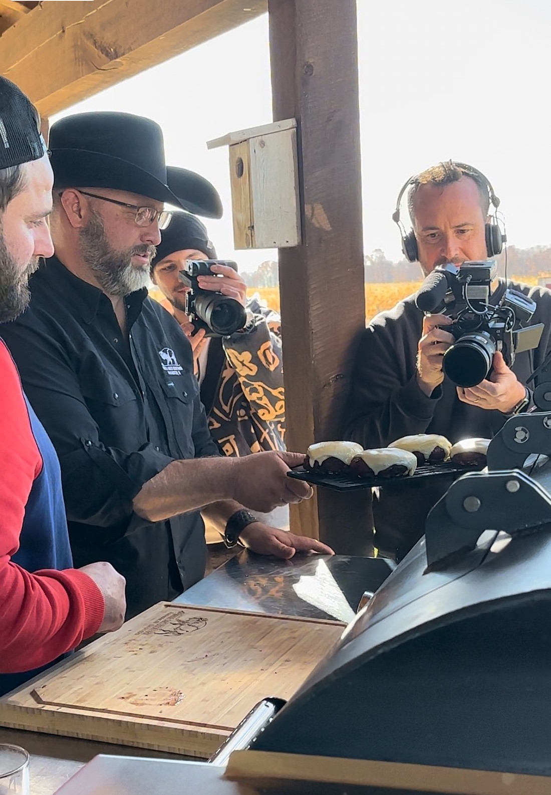 Terry Engstrand (C, in cowboy hat) cooks some American bison burgers with World Burger Champion Joannes “Jo” Richard (L, in red) at White Oaks Bison Farm, Rochester, for an episode of a French cooking show. Photo Provided By Terry Engstrand