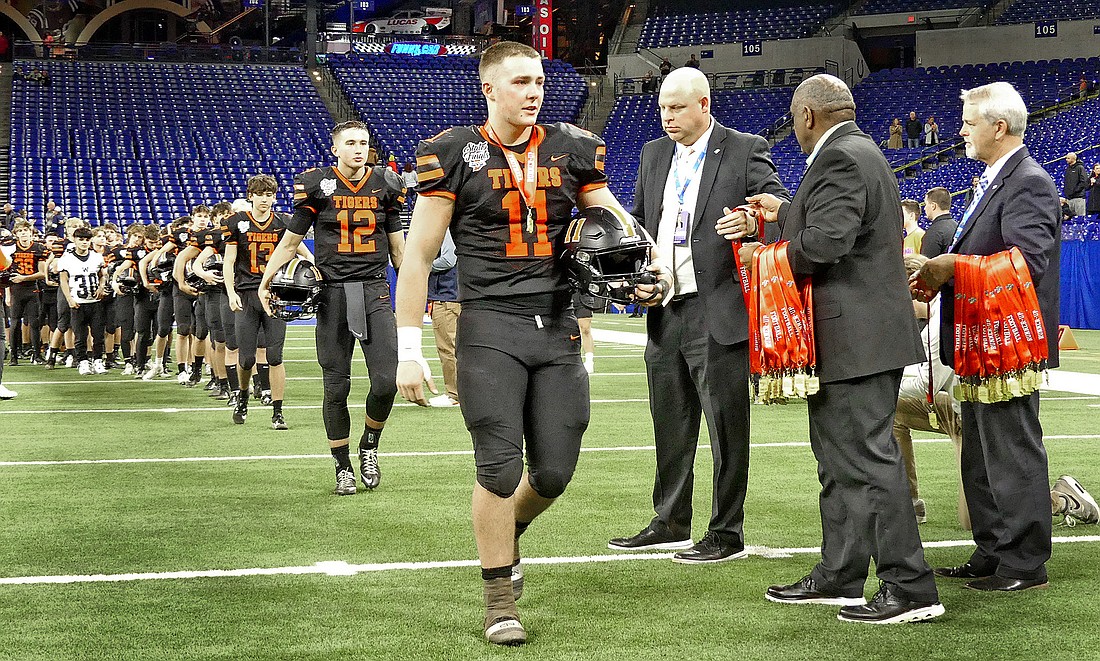 Senior Cohen Heady walks off after receiving his runner-up medal as other Tiger players follow.