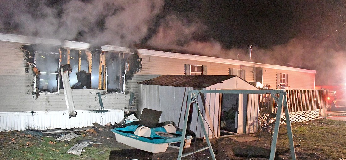 Firefighters work from inside the mobile home during Monday night's fire on Old Colony Road. Photo by Gary Nieter, Times-Union