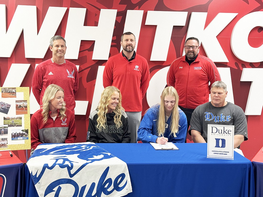 Whitko senior track and field athlete Gwen Howard puts pen to paper at a signing ceremony to celebrate her recent commitment to Duke University. Surrounding Howard are her parents, coaches and Whitko athletic directors. Photo by Connor McCann