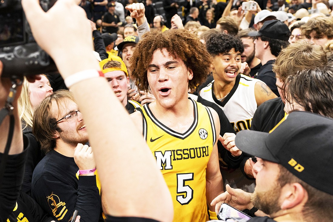 Missouri's T.O. Barrett (5) is surrounded by fans that rushed the court after the team defeated Kansas in an NCAA college basketball game Sunday, Dec. 8, 2024, in Columbia, Mo. (AP Photo/L.G. Patterson)