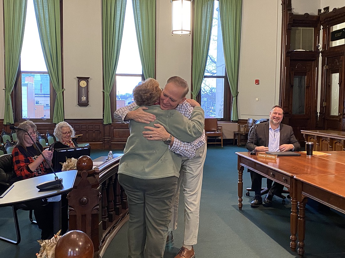 Outgoing Kosciusko County Commissioner Brad Jackson (center right) hugs incoming Kosciusko County Commissioner Sue Ann Mitchell (center left) at the commissioners' meeting on Monday in the Kosciusko County Courthouse's Old Courtroom. Photo by Leah Sander, InkFreeNews