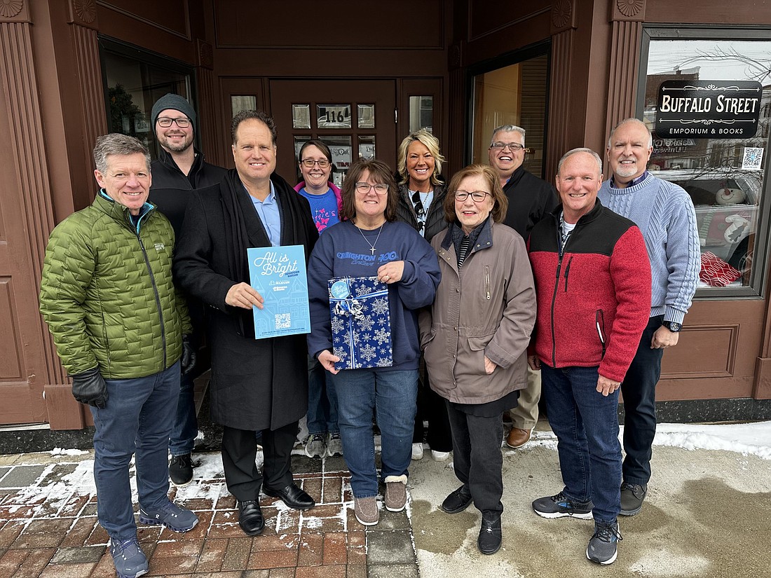 Main Street Warsaw awarded Sharon McIntosh - a customer of Buffalo Street Emporium - the All Is Bright Customer Reward program grand prize of $500 Kosciusko Cash and $1,500 in gift certificates from participating downtown businesses on Monday. Pictured (L to R) are, front row: Bob Vitoux, OrthoWorx; Doug Hanes, 1st Source Bank; McIntosh; Cindy Dobbins, Buffalo Street Emporium; Terry Sweeney, Kosciusko Chamber of Commerce; back row: Matt Smith, Art of Dance; Krista Brown, Maggie’s Coffee & Treats; Michelle Smith Hansen, Glam; Rob Parker, Kosciusko Chamber of Commerce; and Tim Hamann, Male Fashions. Photo by David Slone, Times-Union