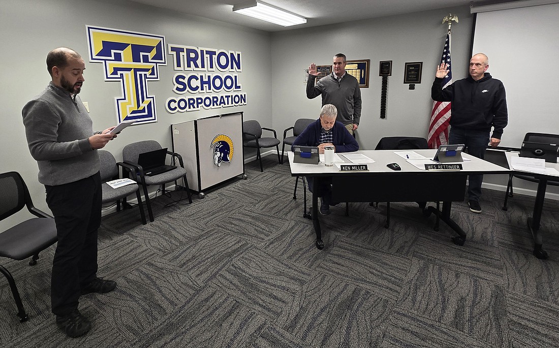 Tom McFarland, business manager for Triton School Corporation (L), swears in Wes Rettinger and Kevin Boyer (both standing) Monday. Sitting is Triton School Board member Ken Miller. Photo by Jackie Gorski, Times-Union