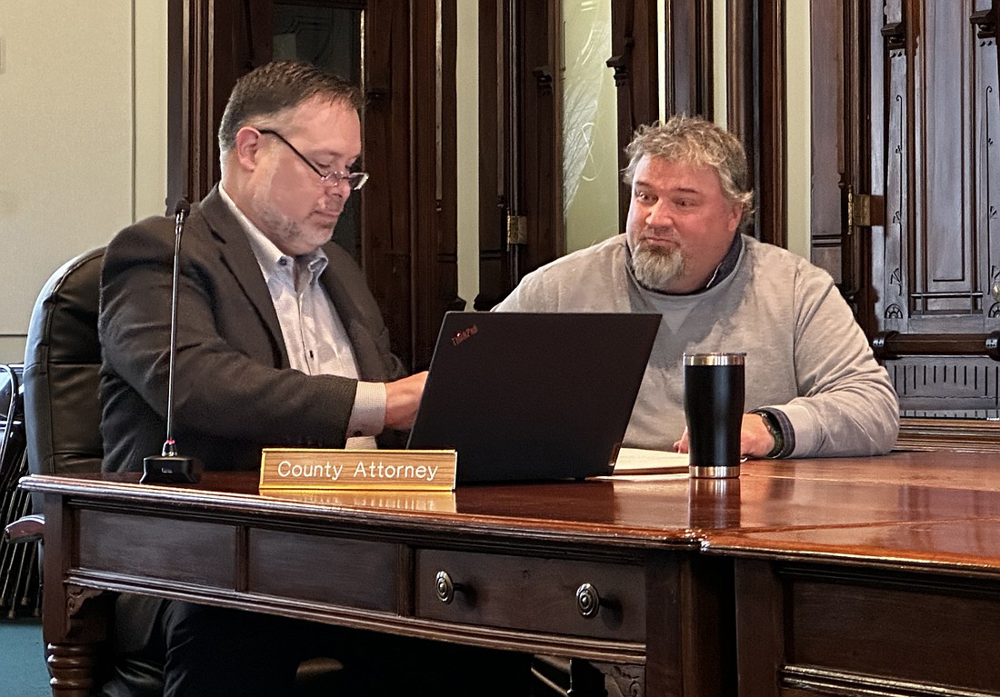 Kosciusko County attorney Ed Ormsby (L) and Highway Department Superintendent Steve Moriarty (R) open bids Tuesday for county road paving projects. Photo by David Slone, Times-Union