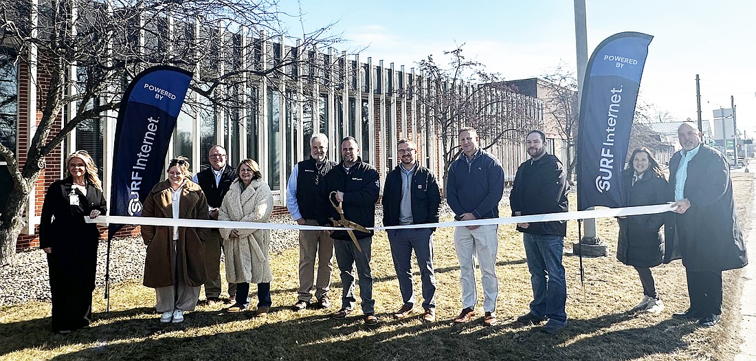 Jordan Holzwart (center, with scissors), Surf Internet regional market manager for eastern Indiana, cuts the ribbon during the ribbon-cutting ceremony Tuesday with the Kosciusko Chamber of Commerce. He is surrounded by Jim Morris (to his right), Surf Internet regional development manager; Chamber staff and ambassadors. Photo by David Slone, Times-Union