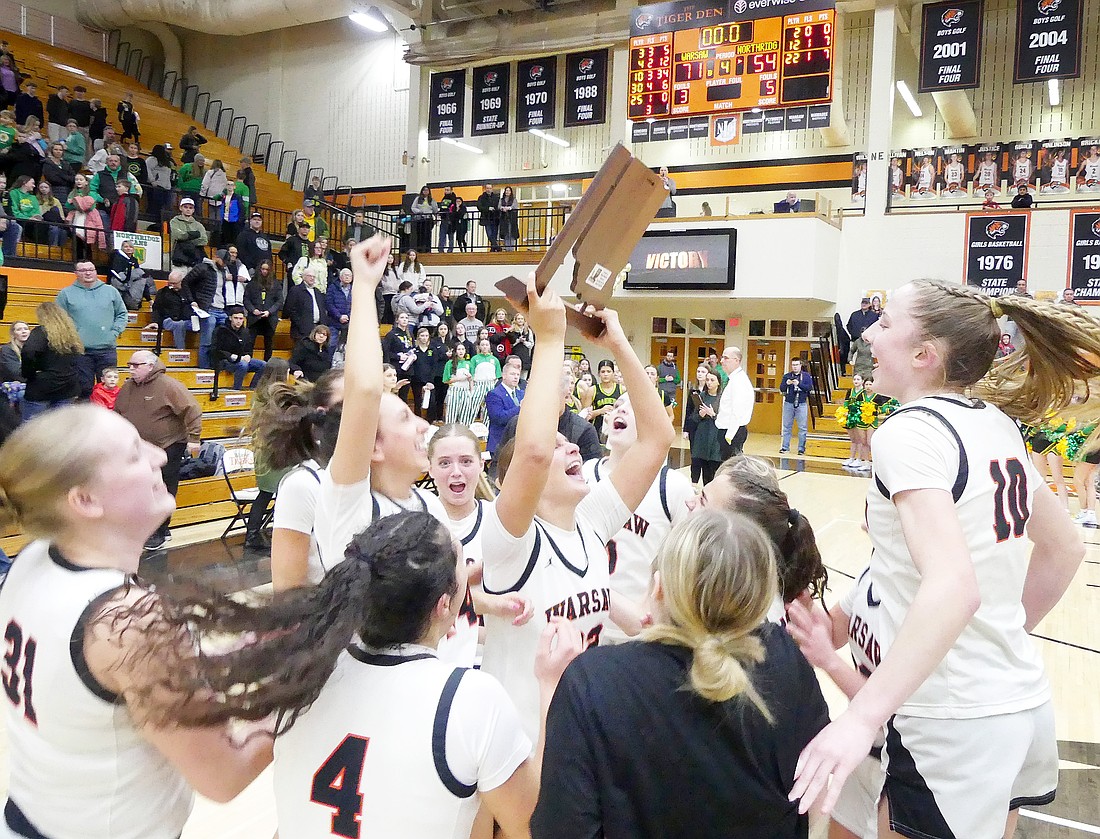 The Warsaw girls basketball team holds up a sectional trophy after defeating Northridge 71-54 on their home court. The Lady Tigers will take on South Bend Washington in Saturday’s regional game.