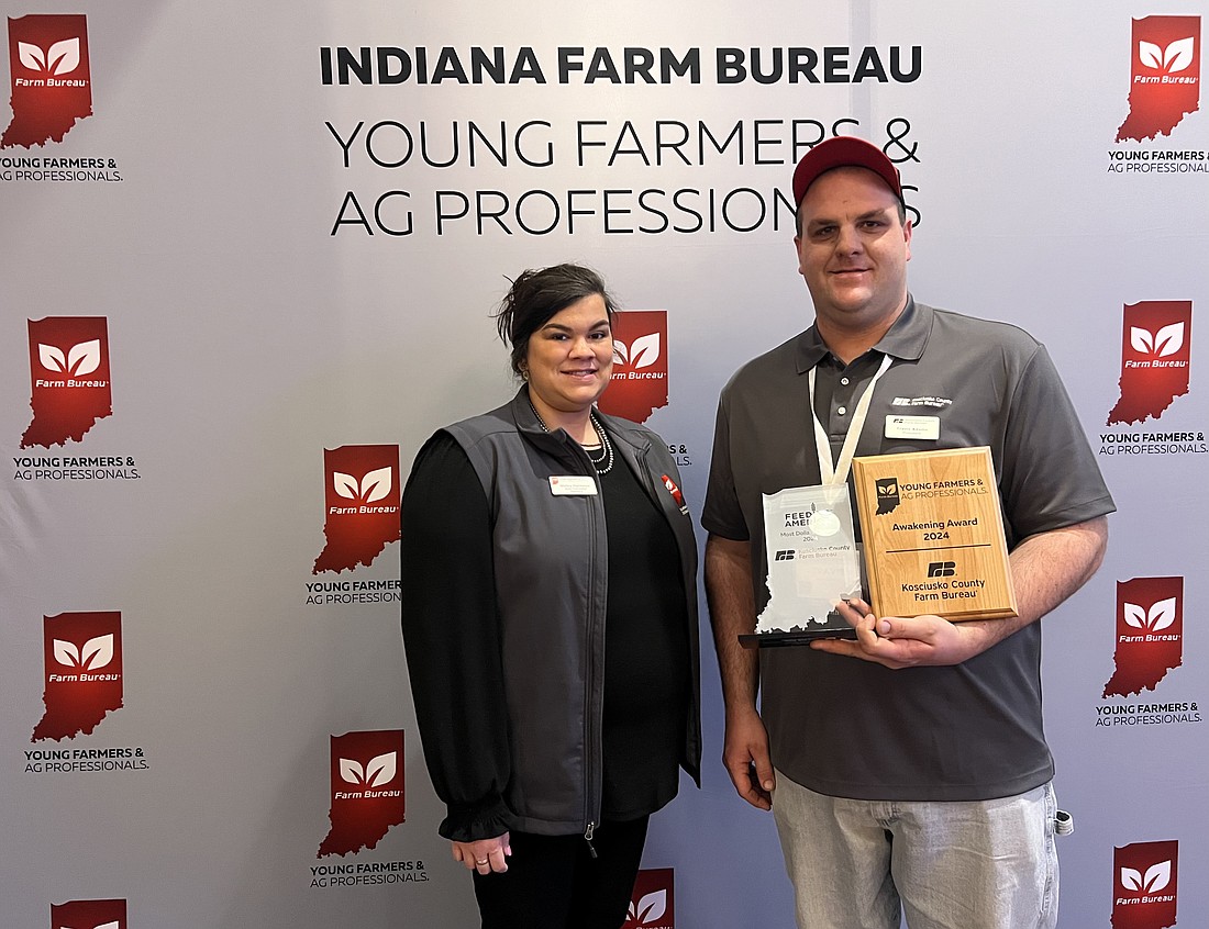 Travis Adams (R), Kosciusko County president, accepts the Awakening Award from Molley Hasenour (INFB YF&AP state chair) and the recognition for Kosciusko County's contributions to Feeding America. Photo Provided.