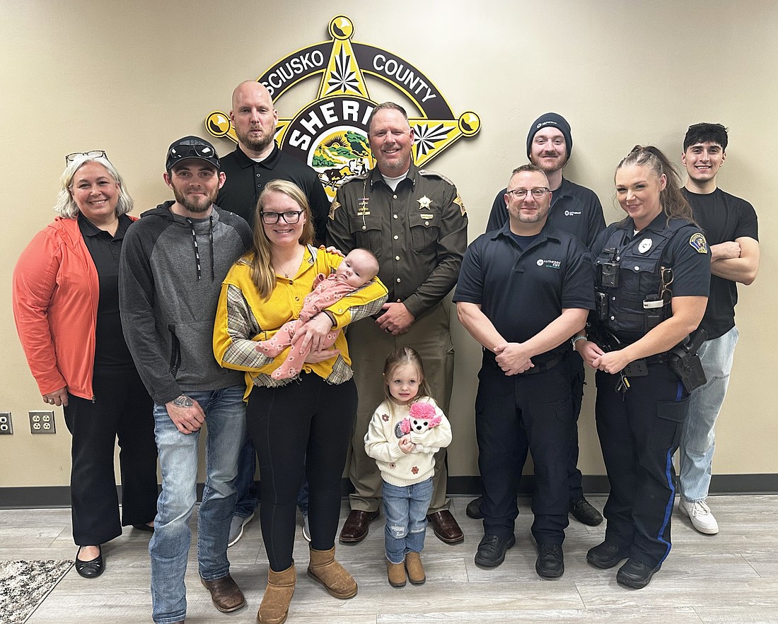 First responders and the Johnson family met Tuesday at the Kosciusko County Sheriff’s Office training room. Dispatcher Nick Carpenter gave Trey Johnson guidance on how to give CPR to his then-8-week-old daughter on Jan. 23, saving her life. Pictured (L to R) are, front row: Trey Johnson, mother Chenee Gaff holding Josiphine Johnson, sister Brylee Walls; Ryan Reed, paramedic, Mandy Escalante, Winona Lake Police Department officer; back row: Amanda See, 911 Operations director; Carpenter; Sheriff Jim Smith; Luke Gunter, Lutheran EMS; and Kevin Terrazas, Warsaw-Wayne Fire Territory. Photo by David Slone, Times-Union