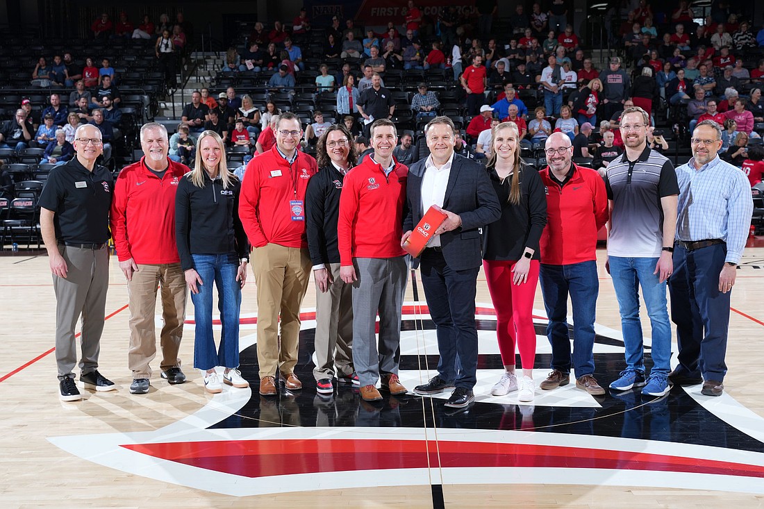 Grace College President Dr. Drew Flamm invited the CEO of Lutheran Kosciusko Hospital, Chad Towner (C) and other hospital staff to the gym floor to acknowledge the hospital’s ongoing support of the institution. Photo Provided.