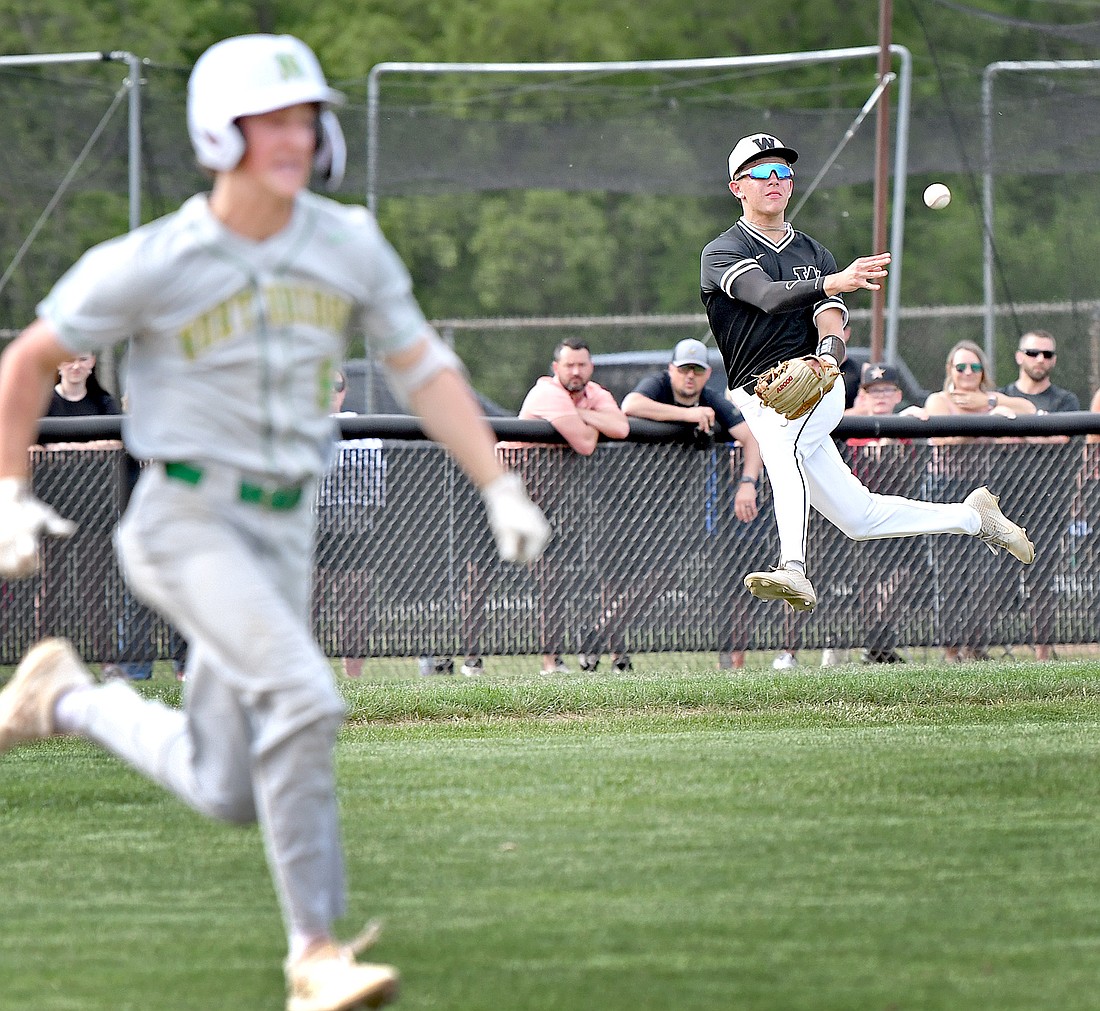 After retrieving a ground ball, junior third baseman Quinton Brock of Warsaw makes a valiant but unsuccessful effor to throw out Northridge batter Aiden Miller...Nieter